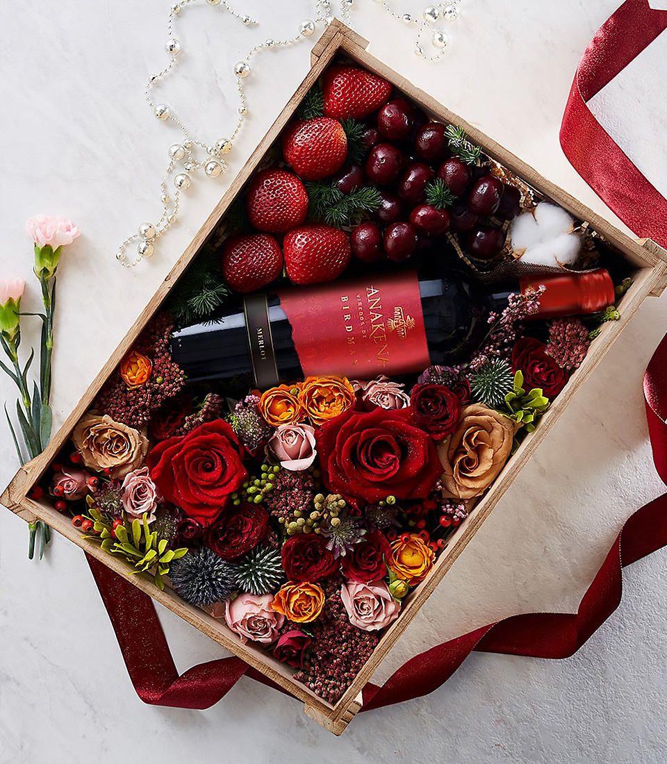 Luxury gift box with red wine, roses, strawberries, cherries, and festive flowers