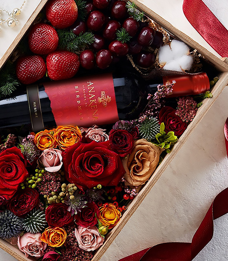 Close-up of a luxury gift box with Anakena red wine, strawberries, cherries, and red roses