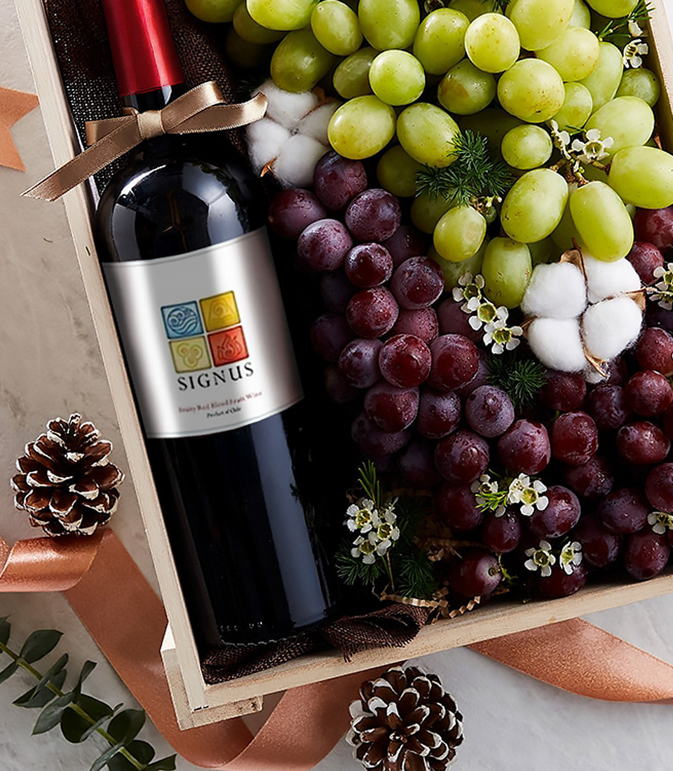 Close-up of Signus red wine with green and red grapes in a wooden gift box