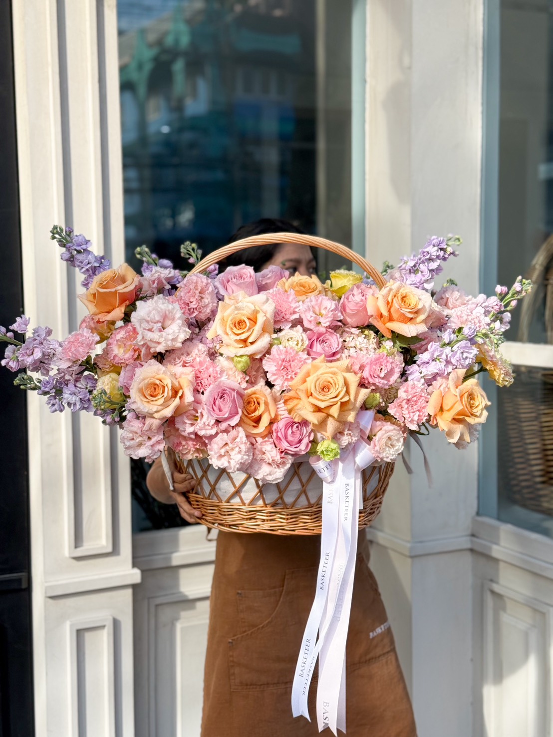 A lavish floral basket featuring pastel roses, carnations, hydrangeas, and stock flowers, elegantly arranged for special occasions.