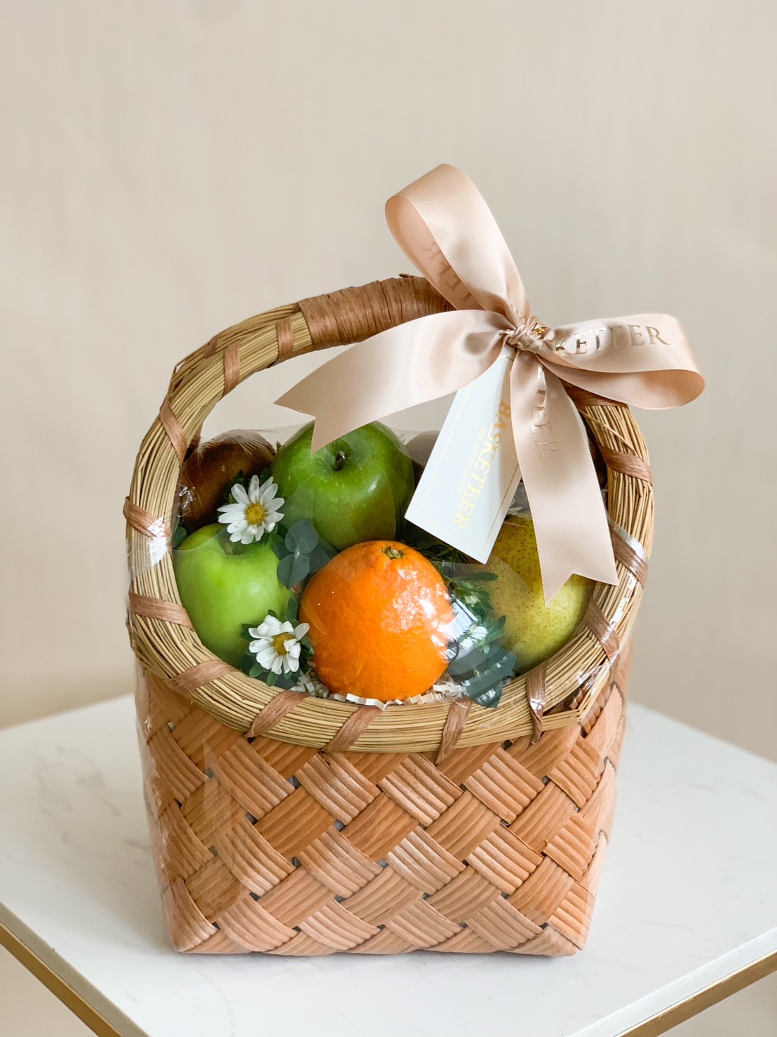 Classic Brown Rattan Gift Basket Filled with a variety of fresh fruits such as green kiwis, oranges, and red apples. and many others Decorated with a shrimp paste colored ribbon bow.