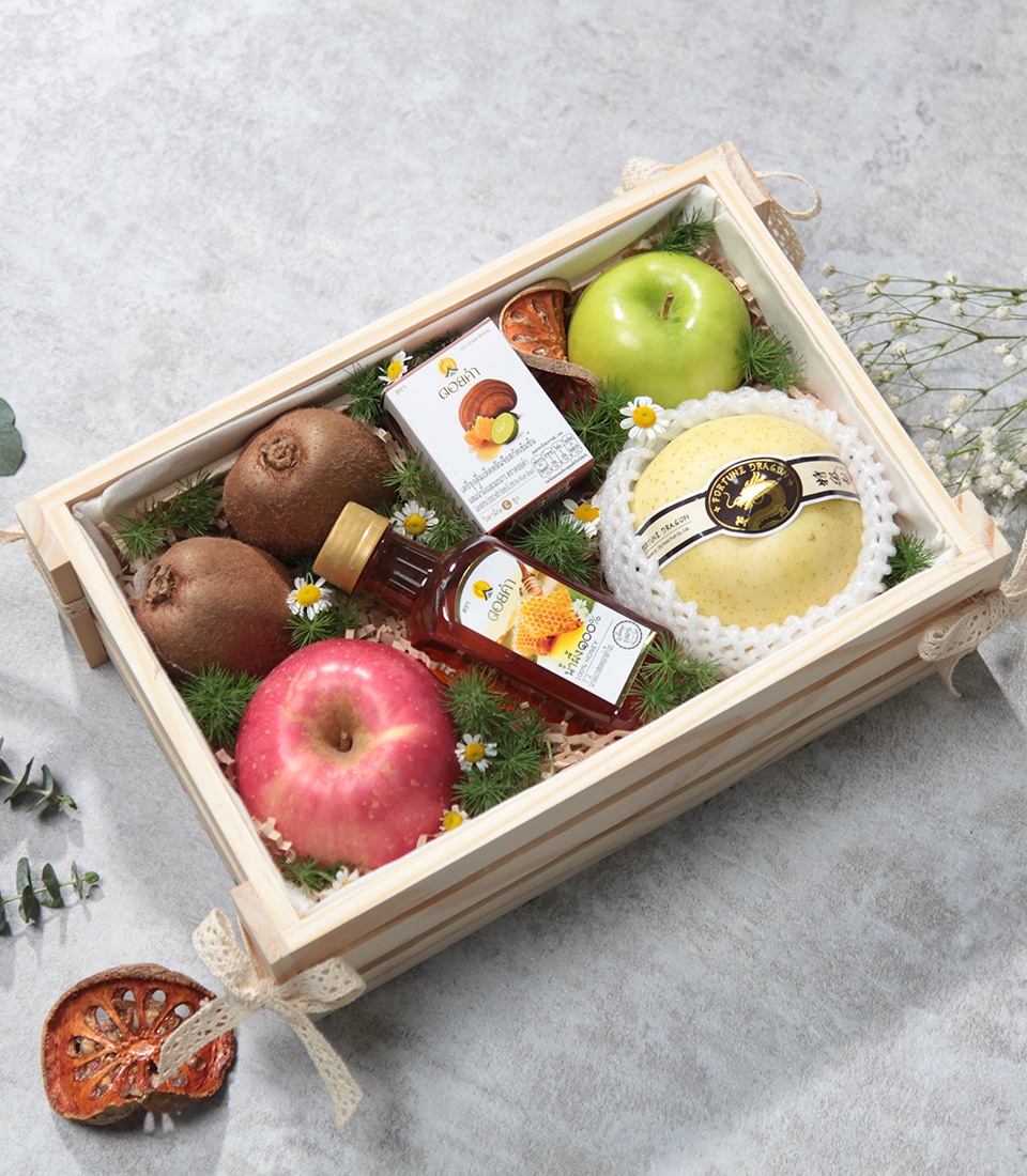 A luxurious Basketeer gift set, featuring an elegant wooden crate brimming with a selection of the finest fruits: a crisp pink apple, a vibrant green apple, a luscious golden melon, and succulent kiwis. Nestled among this bountiful array is a charming bottle of gourmet honey and an exquisite box of premium herbal tea. The arrangement is artfully laid on a bed of aromatic pine needles and adorned with delicate white blossoms, creating an inviting scene that exudes opulence and thoughtfulness.