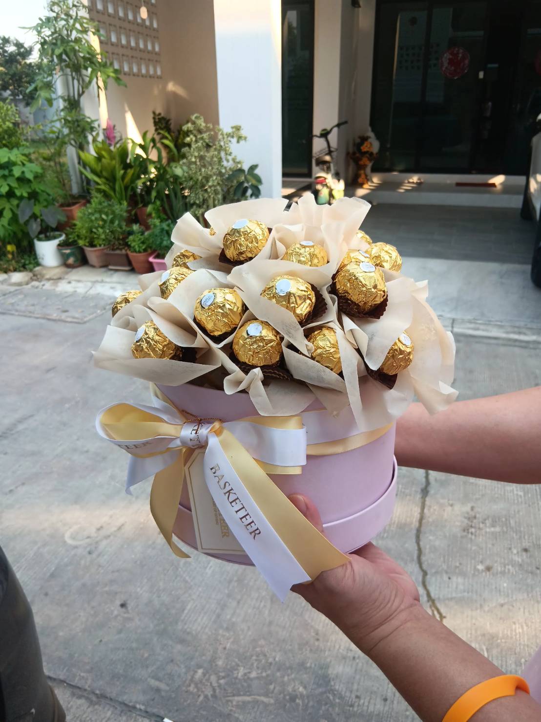 A beautifully arranged Ferrero Rocher chocolate bouquet in an elegant pastel pink round gift box, adorned with luxury satin ribbons, making it a perfect gift for special occasions.