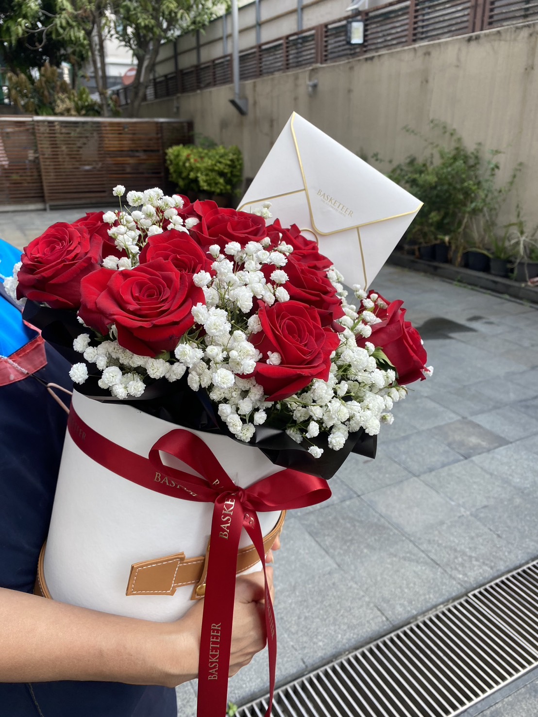 Elegant red roses and baby’s breath flowers arranged in a luxury hatbox with a Basketeer signature ribbon and gift card—perfect for romantic occasions.