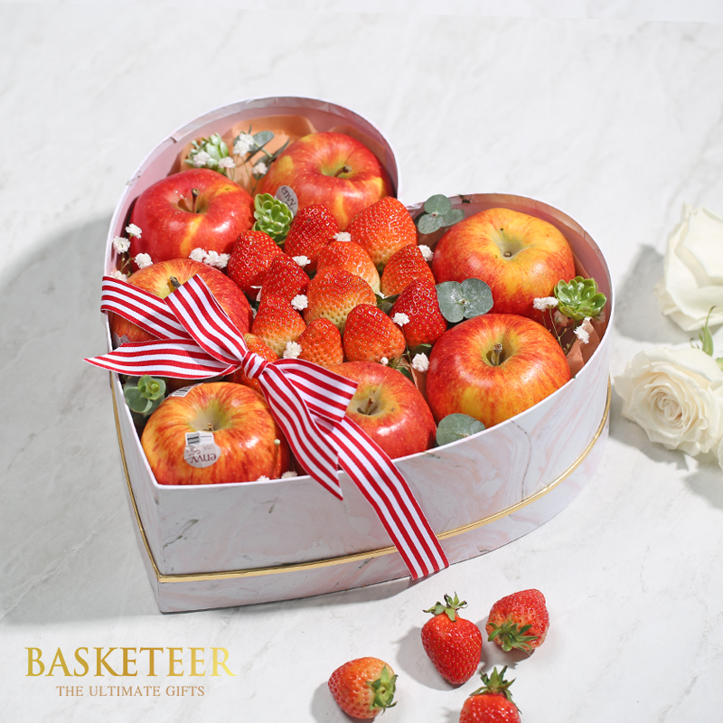 Mixed apples and strawberrys in a heart box with bow