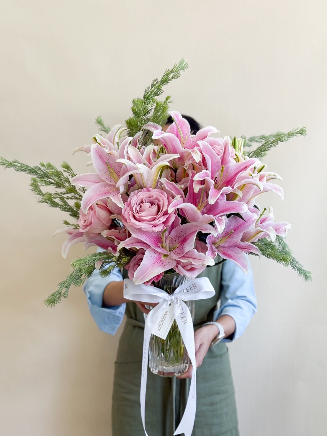 Elegant vase of pink lilies and roses with fresh greenery.