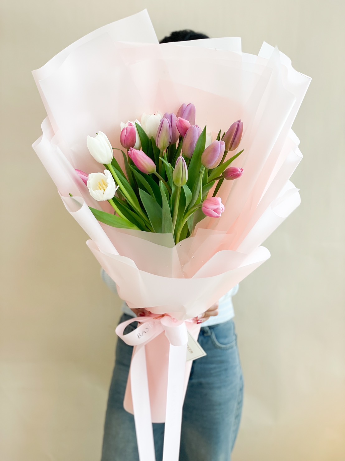 A stunning pastel tulip bouquet featuring soft pink, white, and lilac tulips, elegantly wrapped in pink paper with a delicate ribbon – perfect for romantic gestures and celebrations.