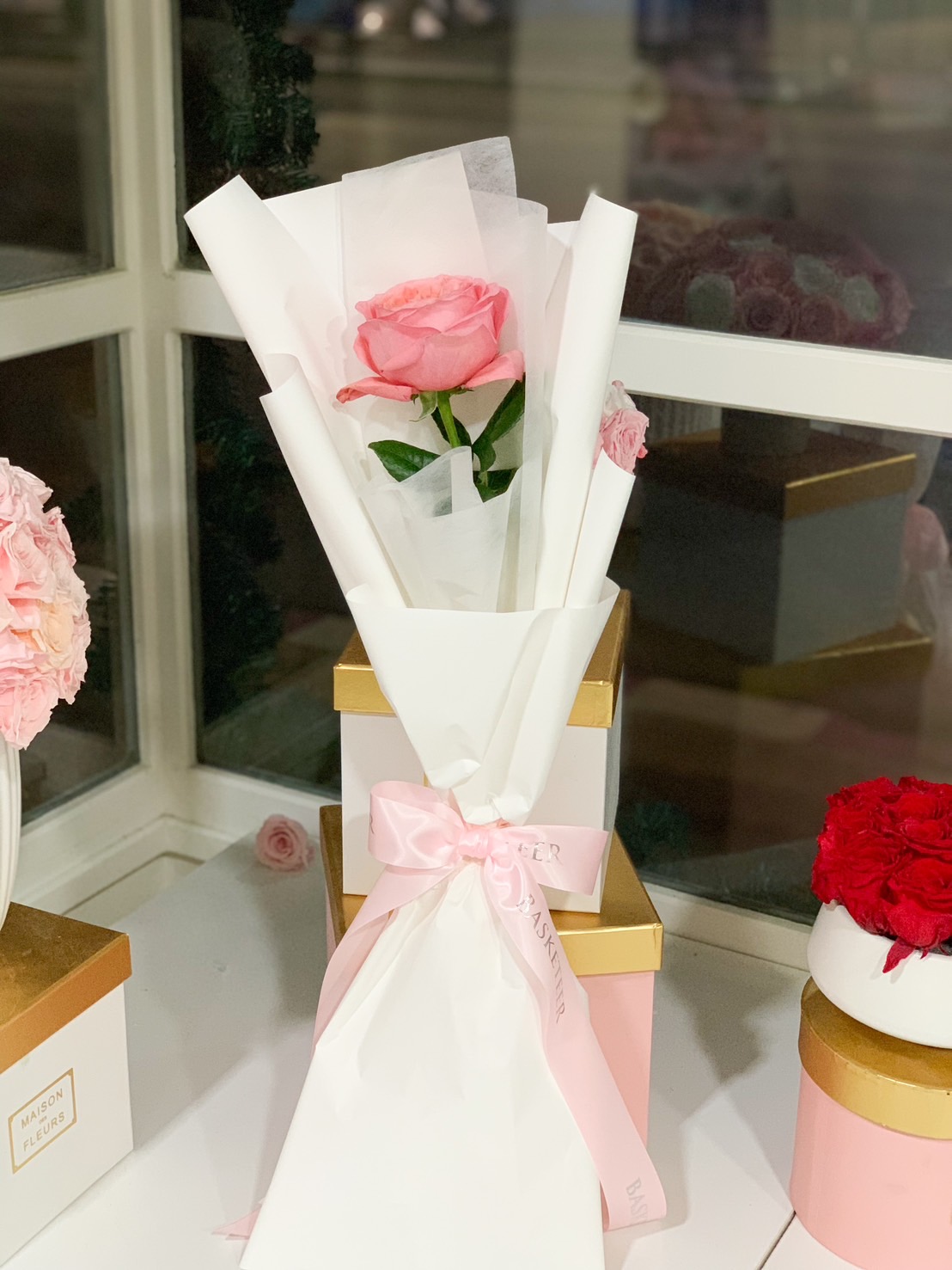 A single pink rose elegantly wrapped in white paper, tied with a soft pink satin ribbon, perfect for romantic gifts, anniversaries, and Valentine’s Day surprises.