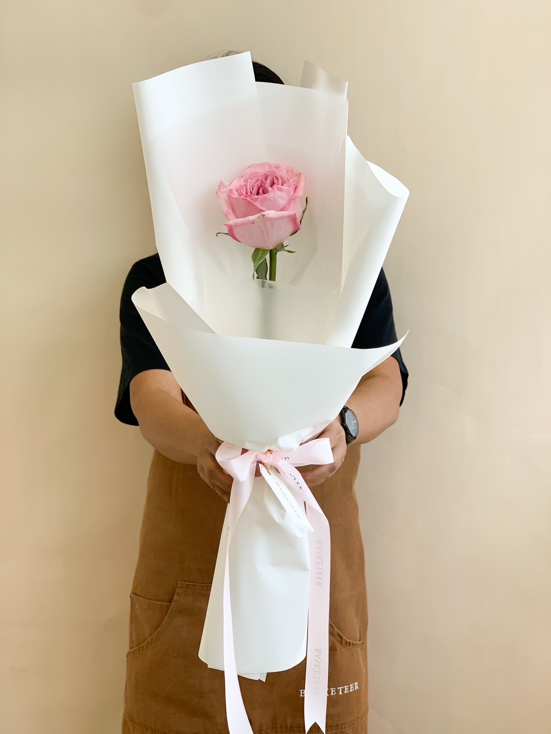 A single pink rose beautifully wrapped in a minimalist white bouquet, tied with a delicate pink ribbon. A perfect gift for romantic gestures, anniversaries, proposals, or special occasions.