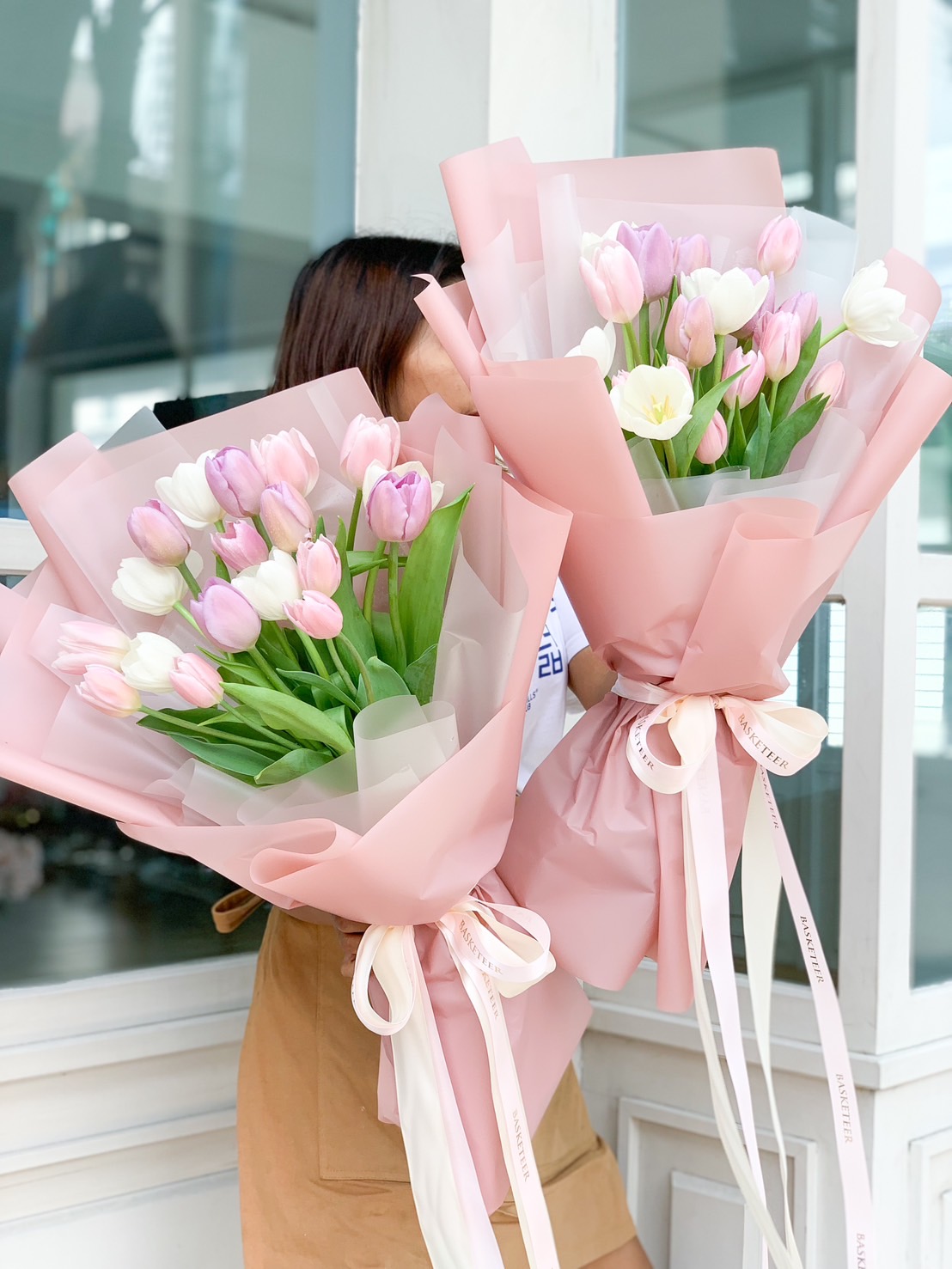 A stunning pastel tulip bouquet featuring soft pink, white, and lilac tulips, elegantly wrapped in pink paper with a delicate ribbon – perfect for romantic gestures and celebrations.