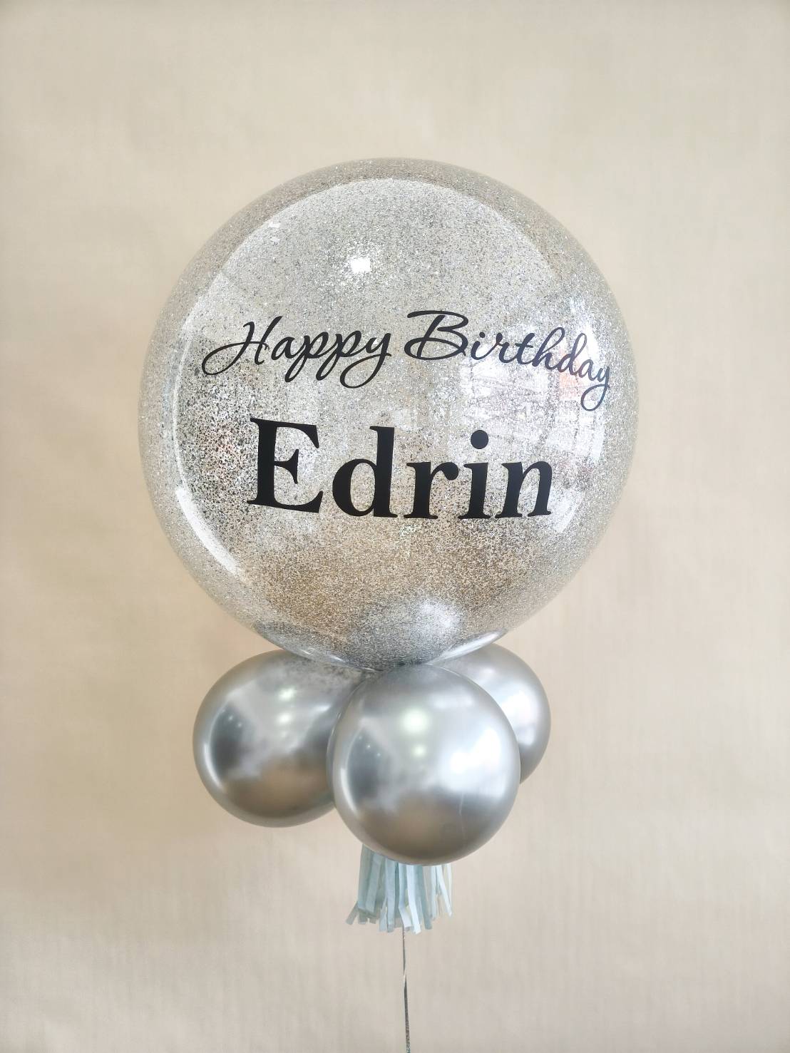 Silver glitter bubble balloon with personalised Happy Birthday message and metallic silver balloons at the base.