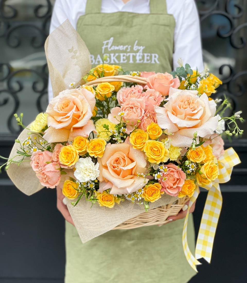 Bright flower basket of orange and yellow roses with gingham ribbon, perfect for congratulations.