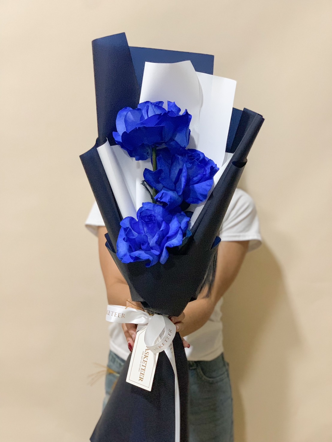 A luxurious bouquet of deep blue roses, wrapped in elegant navy and white paper, tied with a satin ribbon. A bold and sophisticated floral arrangement.