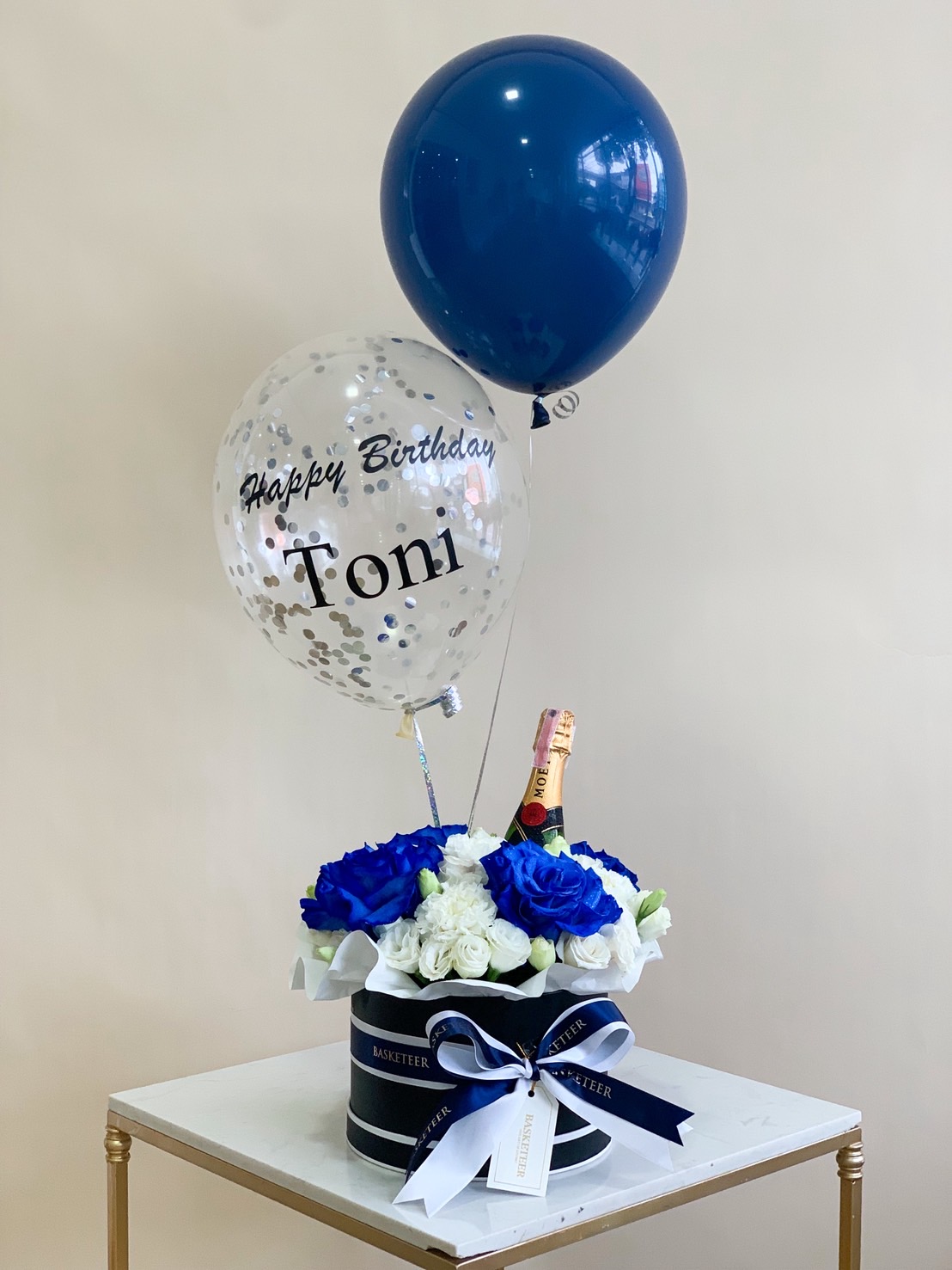 Birthday gift box with blue and white roses, Moët champagne, and Happy Birthday balloons