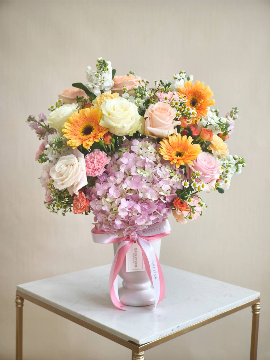 Flower vase with peach roses, pink hydrangeas, orange gerberas, cream roses, and assorted blooms in pastel tones