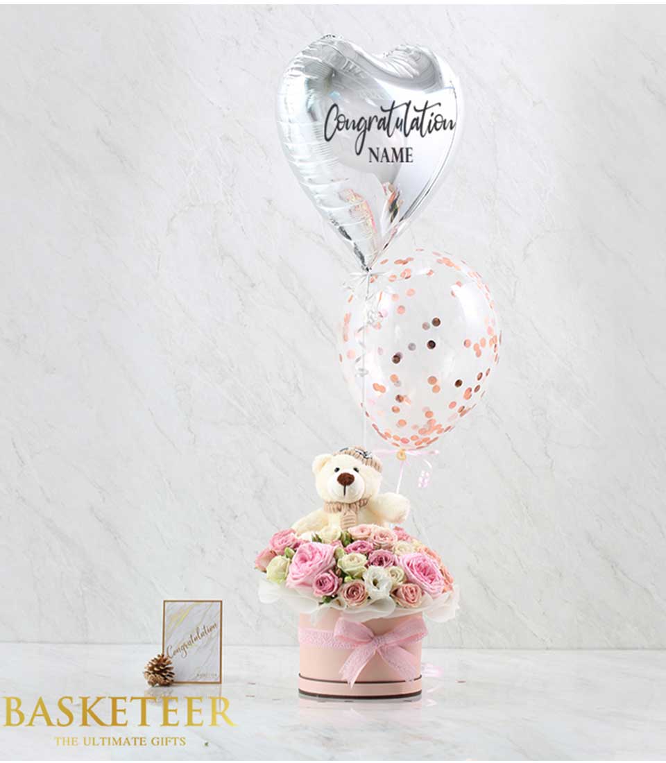 Discover sweetness overload with our charming gift box set featuring sweet pink flowers, a cuddly teddy bear, and elegant gray heart balloons. Perfect for expressing love and affection.