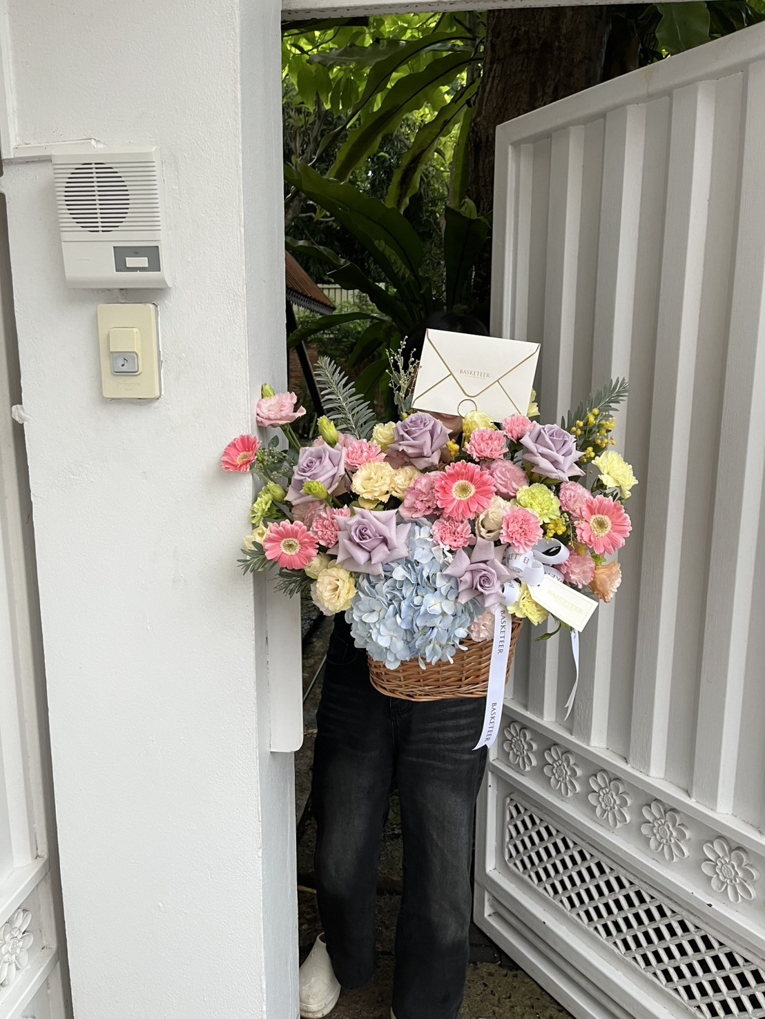 Pastel flower basket with roses, hydrangeas, gerberas, and carnations in soft hues, arranged in a natural wicker basket