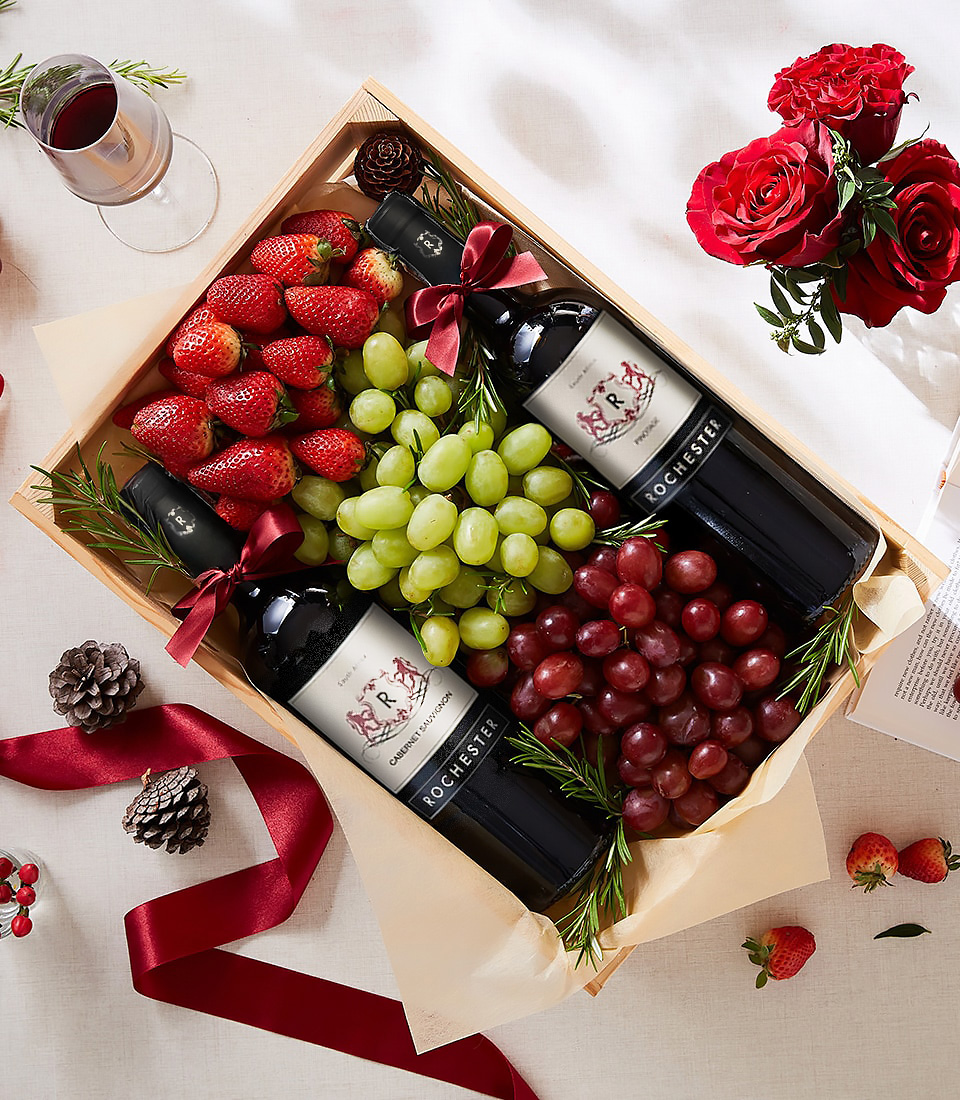 Gift box with two bottles of Rochester Cabernet Sauvignon, fresh strawberries, green grapes, red grapes, rosemary, and red ribbon