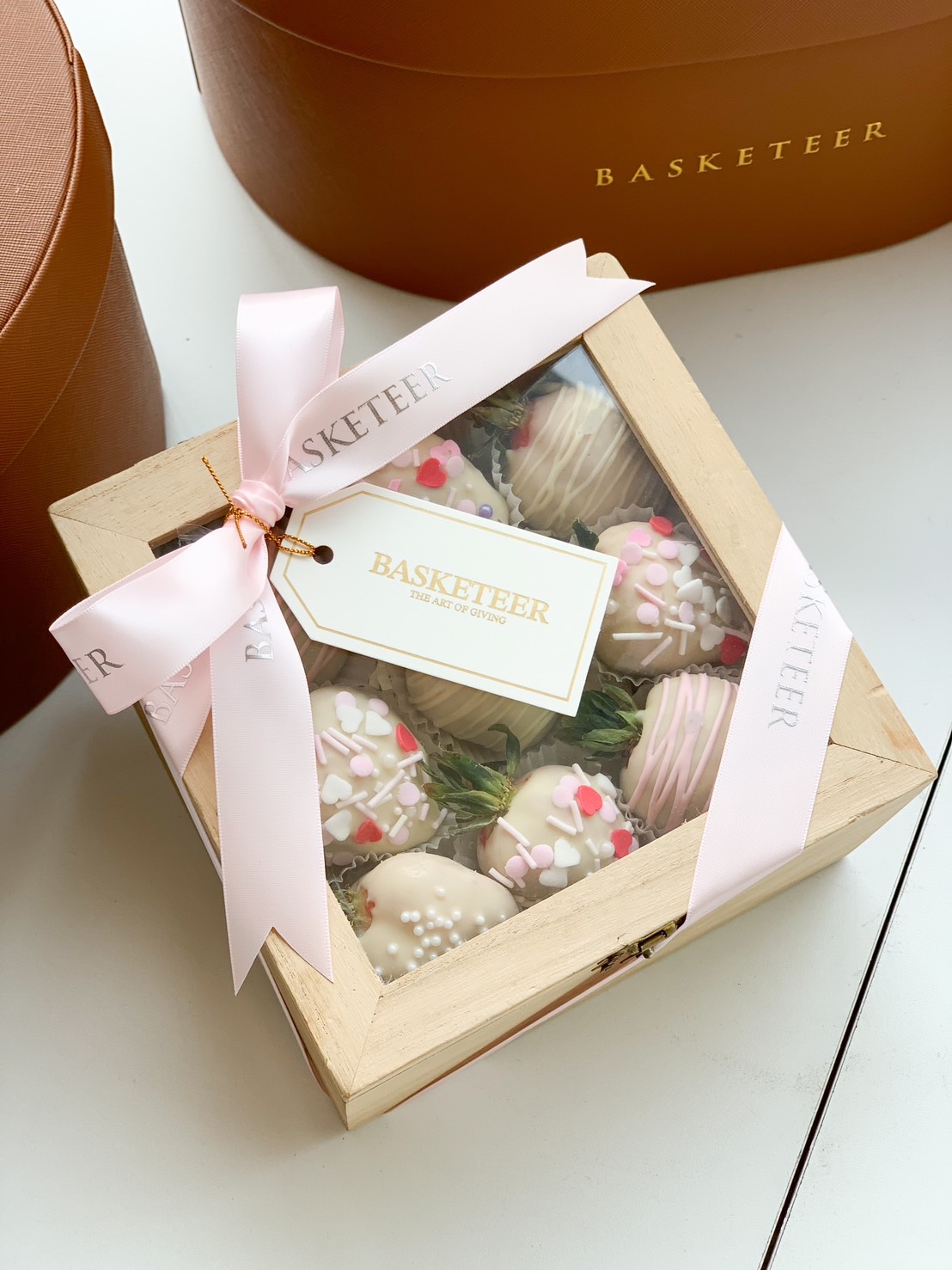 A beautifully packaged wooden gift box filled with white chocolate-covered strawberries, decorated with sprinkles and heart toppings.