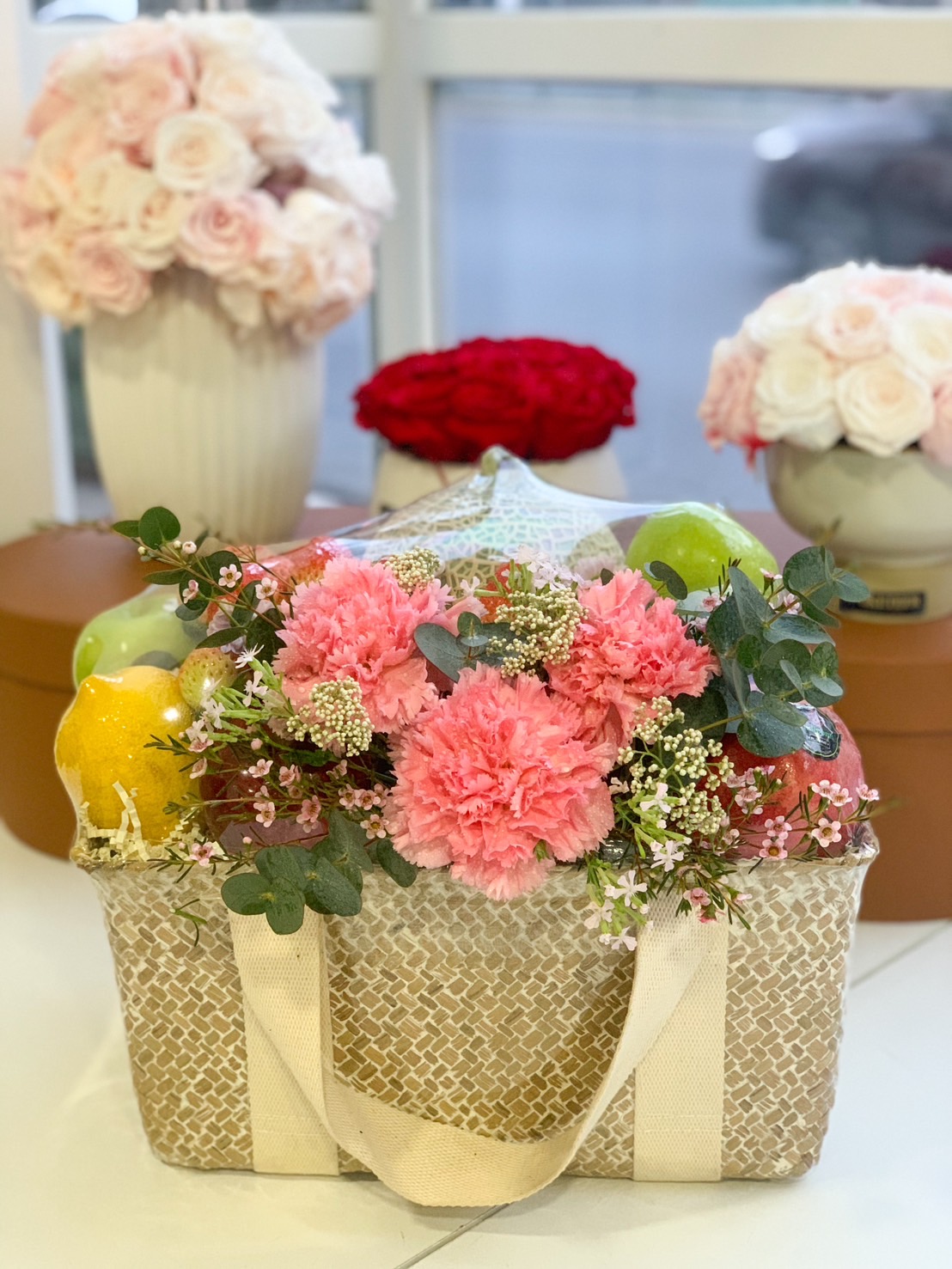 Luxury fruit and floral gift basket with pink carnations and green apples.