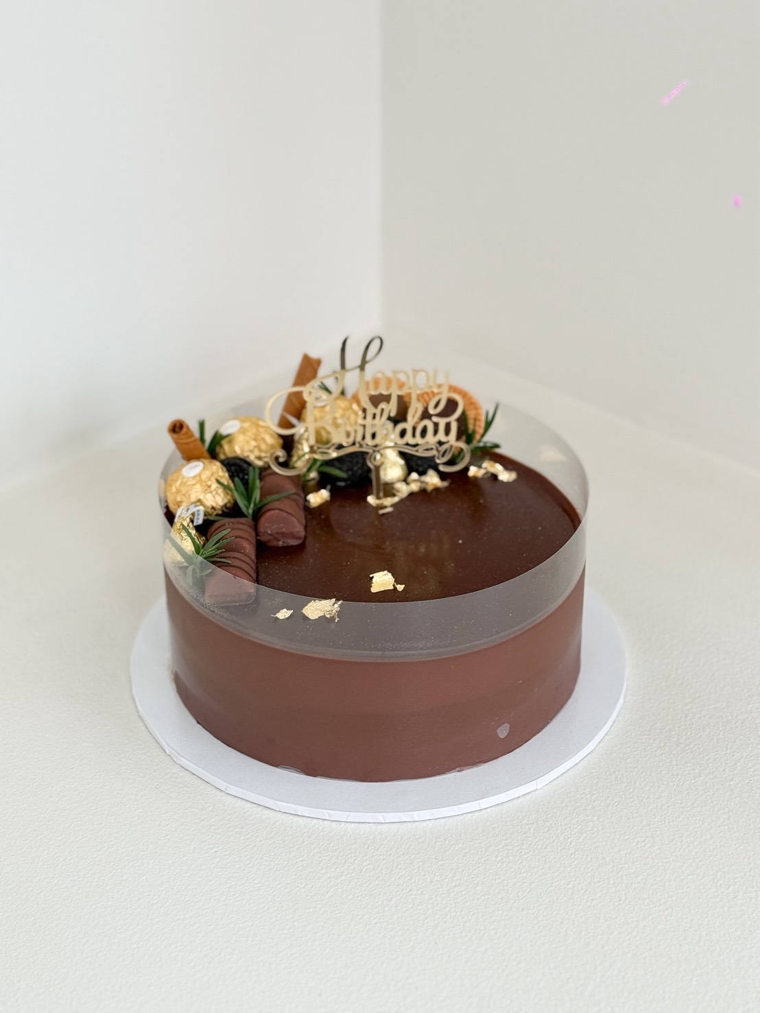 Luxury chocolate mousse cake decorated with Ferrero Rocher, chocolate bars, wafer rolls, and edible gold leaf, with Happy Birthday topper