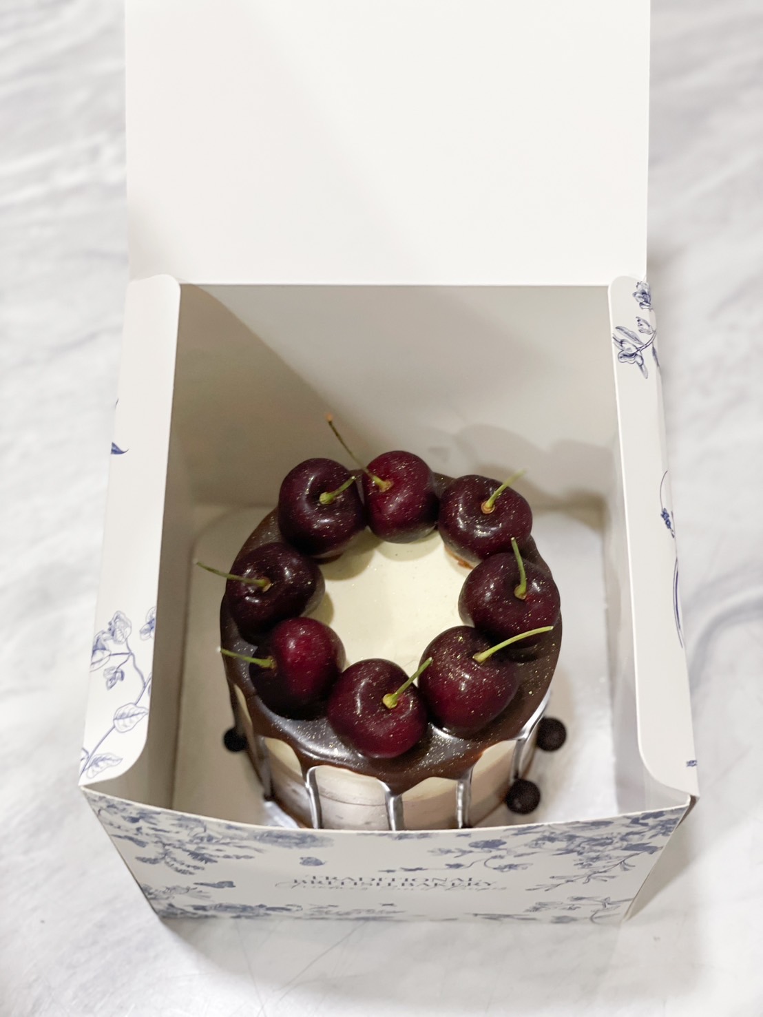 Gourmet Cherry Chocolate Drizzle Cake with fresh cherries on top and chocolate glaze in an elegant box.