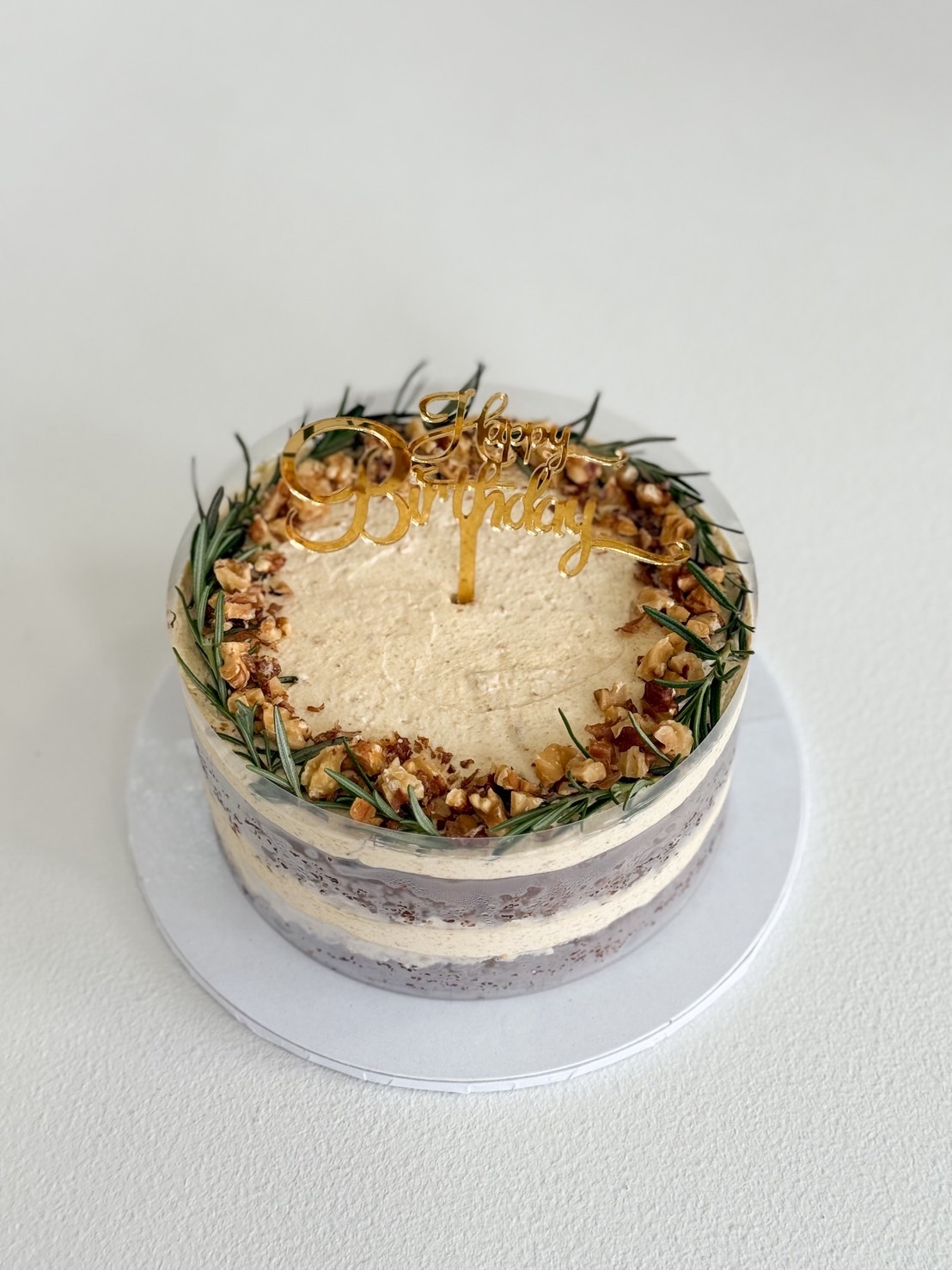 Rustic-style walnut coffee layer birthday cake with buttercream and rosemary decoration