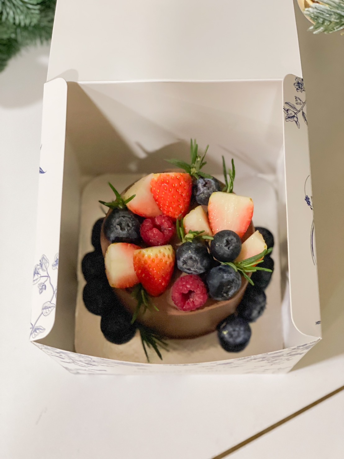 Mini cake decorated with fresh strawberries, blueberries, and raspberries in a gift box by Basketeer.