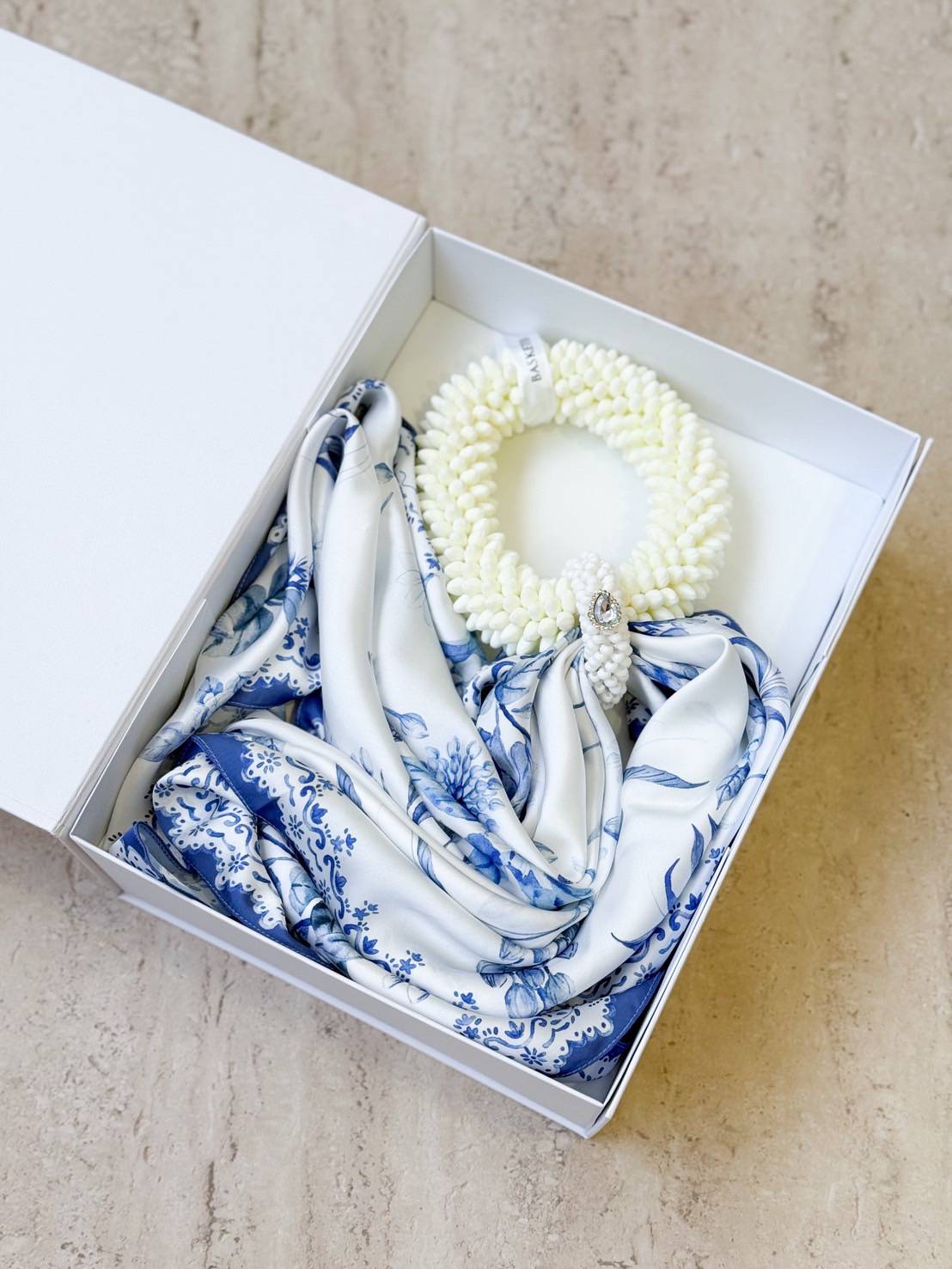 Luxury gift set featuring a white jasmine garland and blue-and-white patterned silk scarf, presented in an elegant white box.