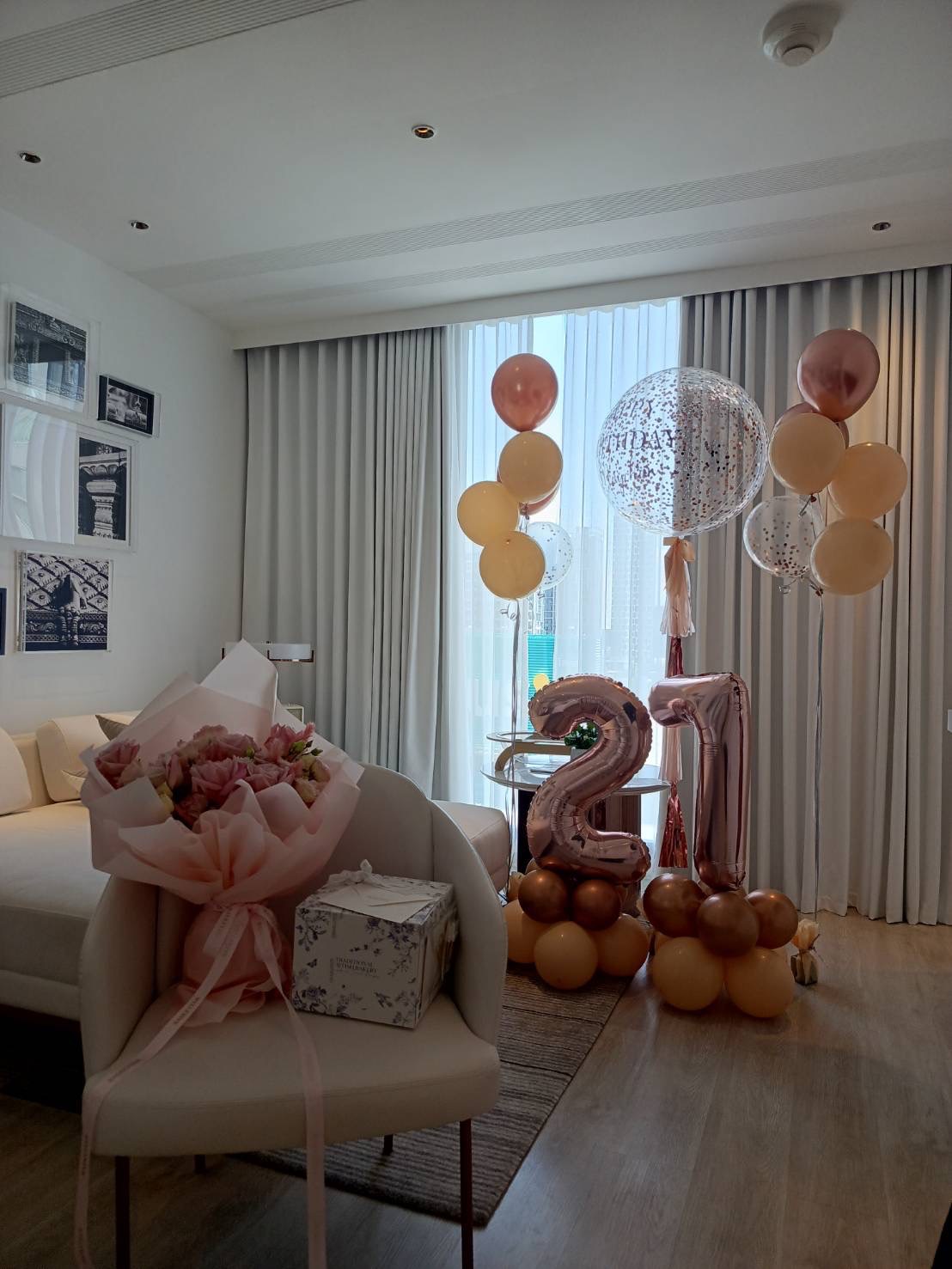 A hotel room decorated for a 25th birthday celebration, featuring pink and gold balloons, including a large 