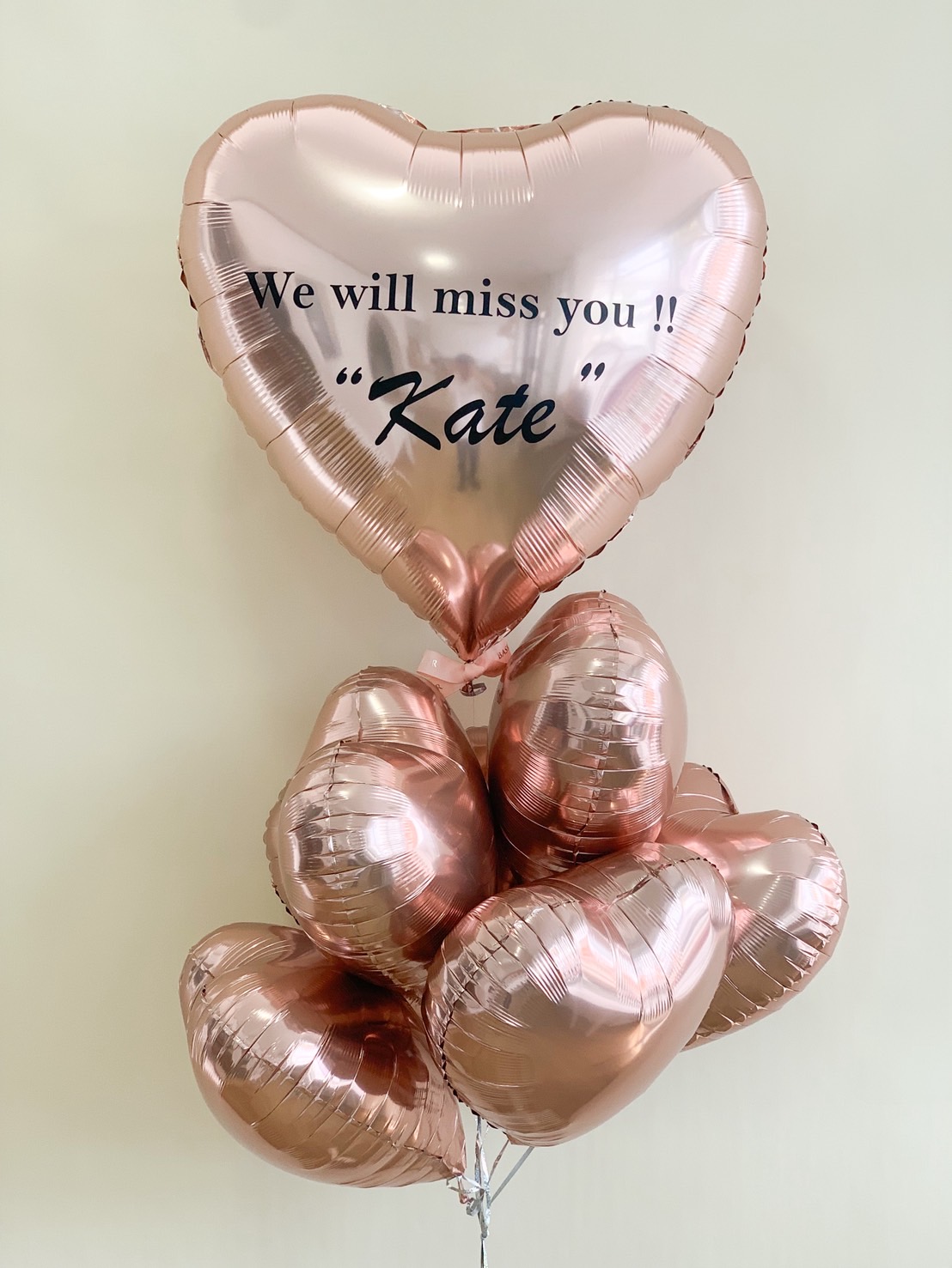 Rose gold heart-shaped balloons with “We will miss you!! Kate” farewell message.