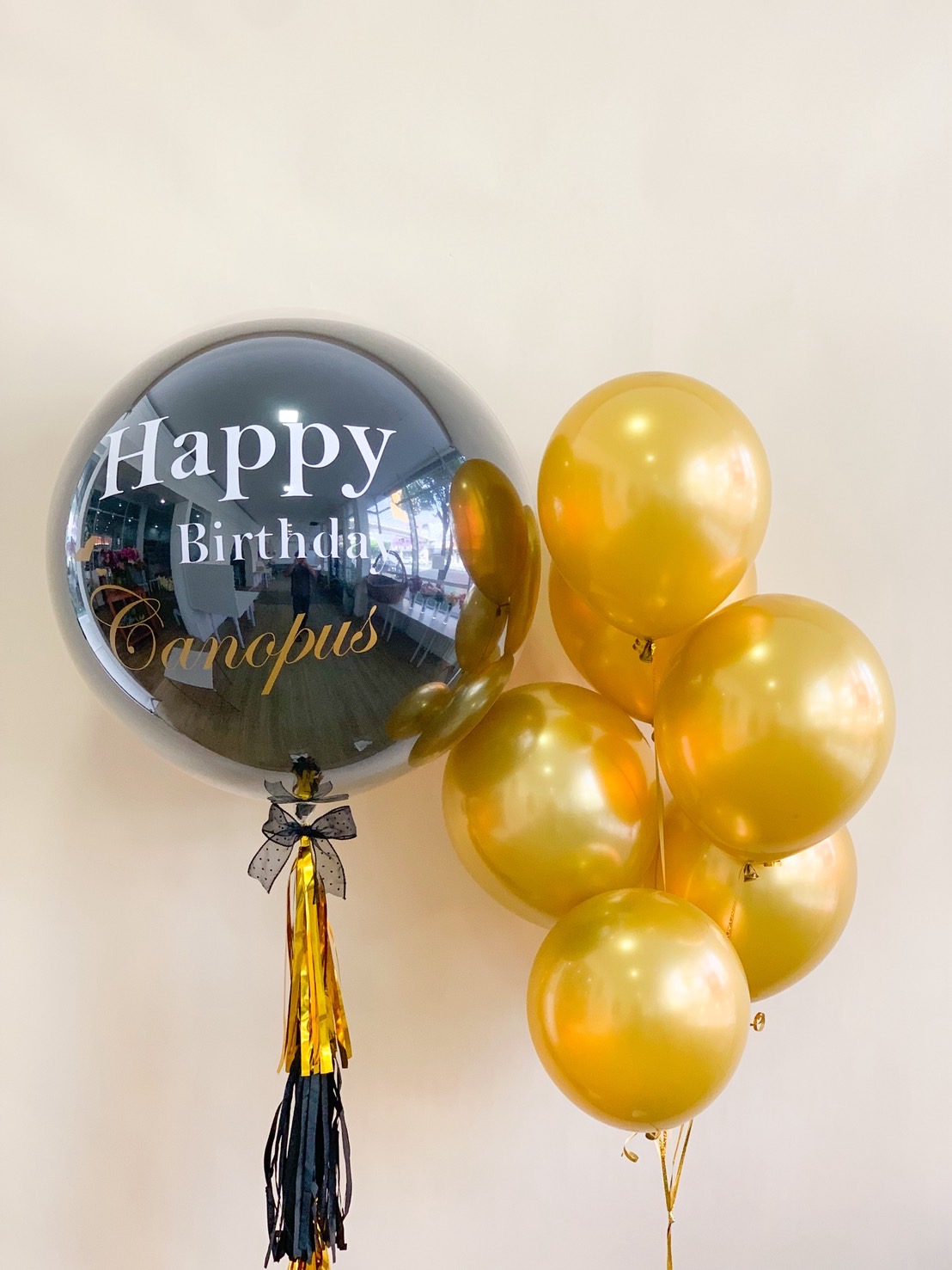 Elegant black and gold birthday balloon arrangement with personalized message and tassel ribbon.