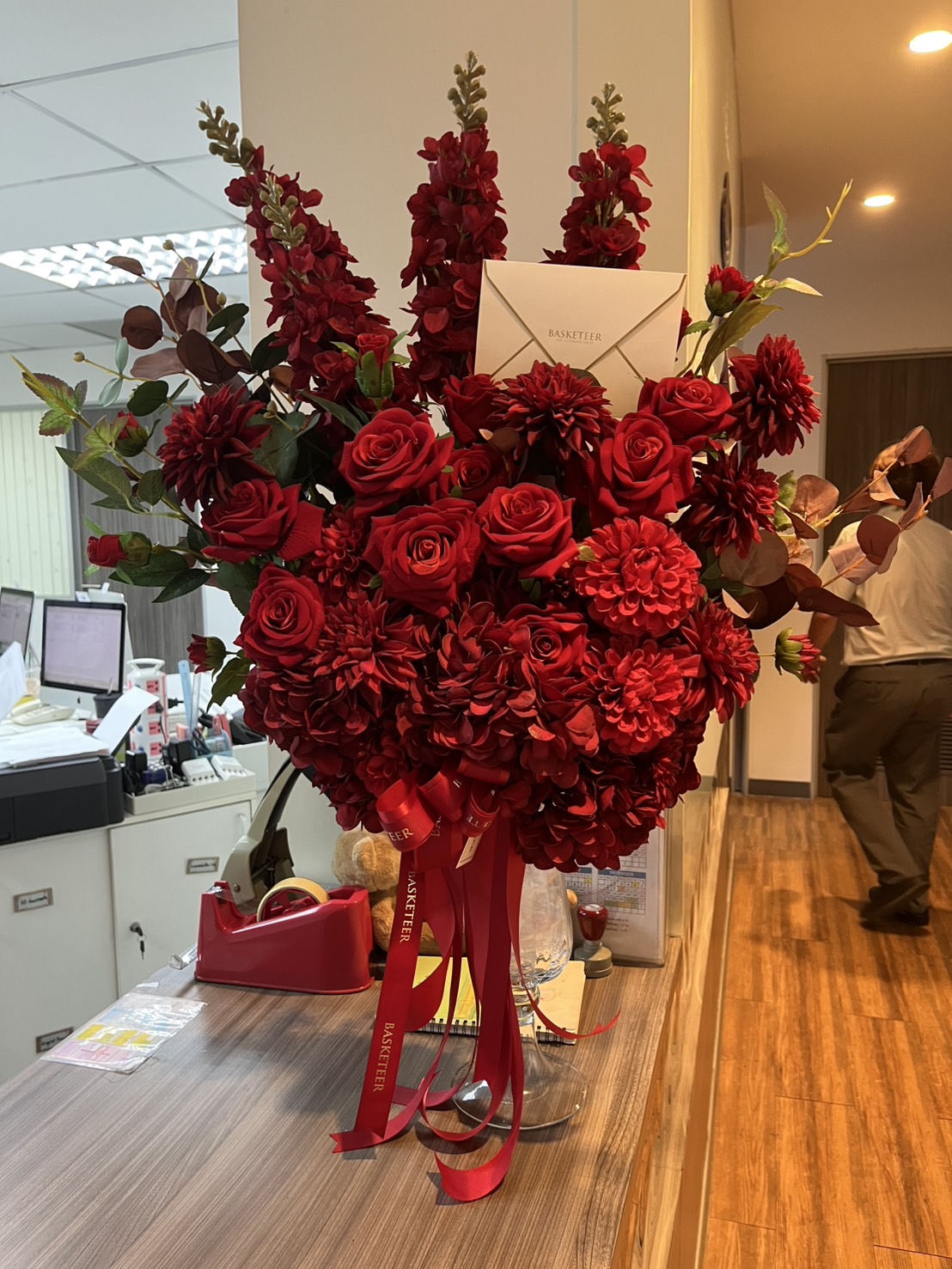 Luxury red vase arrangement with red roses, dahlias, snapdragons, and foliage, decorated with Basketeer ribbon – elegant congratulatory gift.