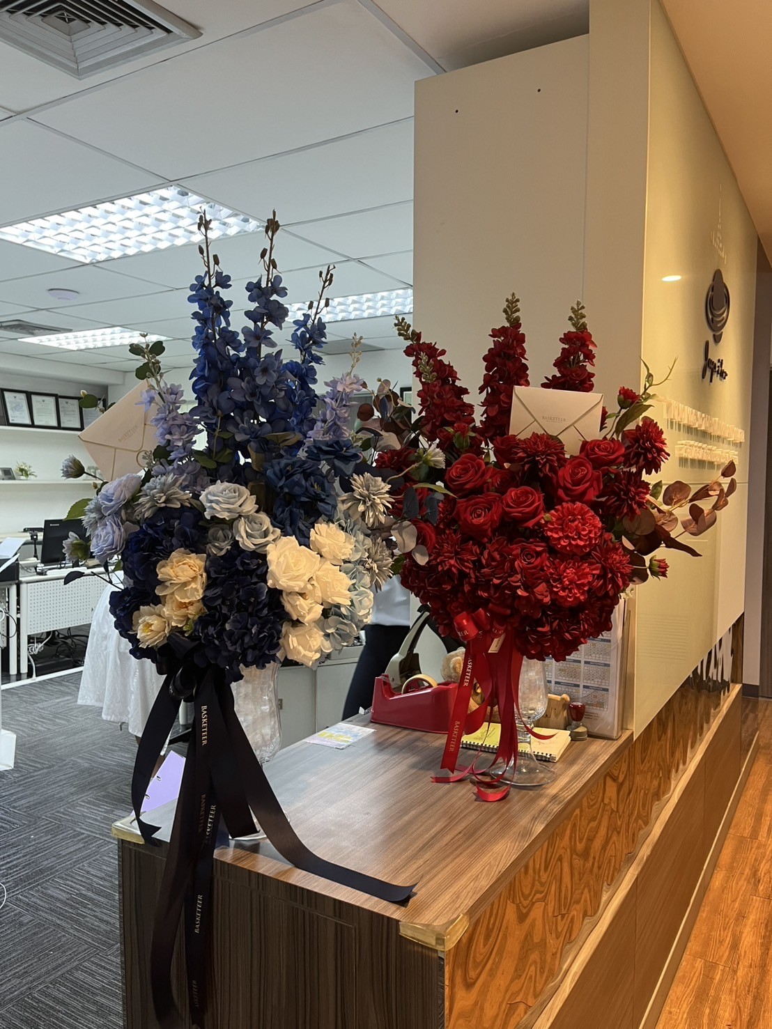 Luxury vase flower set with blue-white roses, hydrangeas, delphiniums, and red roses with dahlias, decorated with Basketeer ribbons.