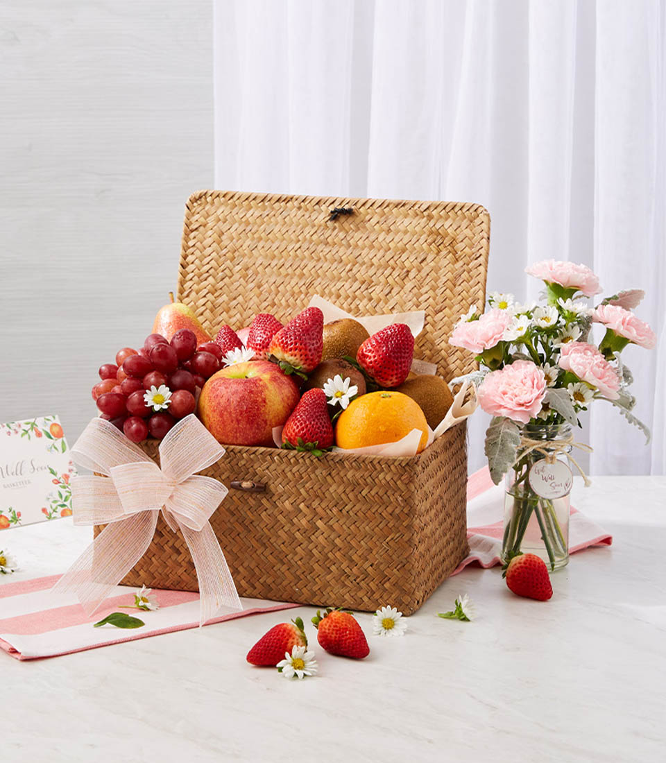 Fresh Fruits In The Woven Hamper With A Small Pink Flowers Vase