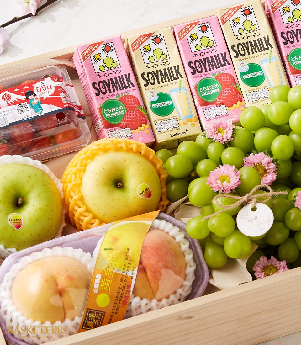 The Premium Fruit Box Elysium by Basketeer exudes luxury and sophistication. This elegantly crafted wooden box is a cornucopia of delectable delights, featuring plump grape tomatoes, a luscious bunch of green grapes adorned with delicate pink blossoms, and a radiant yellow apple. Nestled carefully within are two peaches cradled in protective netting, while four vibrant cartons of premium soy milk complete this enticing ensemble. A ribbon embossed with the prestigious Basketeer logo adds a final touch of opulence to this exquisite gift set.
