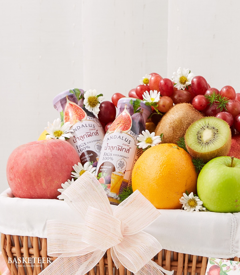 A luxurious wicker basket brimming with an exquisite selection of fresh fruits, including crisp apples, sun-kissed oranges, succulent kiwis, and a lavish cluster of grapes. The arrangement is elegantly embellished with delicate white blossoms. Nestled within this opulent display are two bottles of Andalus fig juice, promising a tantalizing taste experience. A sophisticated cream-colored bow graces the front of the basket, while the Basketeer logo adds an air of distinguished refinement to this inviting ensemble.