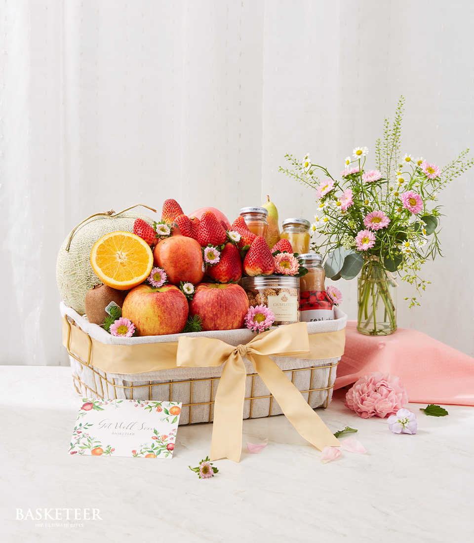 Fresh Fruits, Fruit Drinks And Cashew Nuts In The Golden Steel Frame Basket With A Small Pink Flowers in Vase