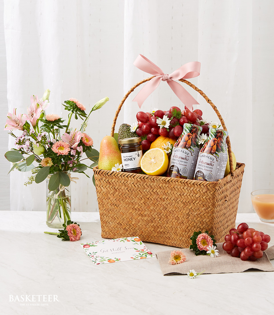 Fresh Fruits And Healthy Drinks In The Woven Basket With A Small Soft Orange Flowers Vase