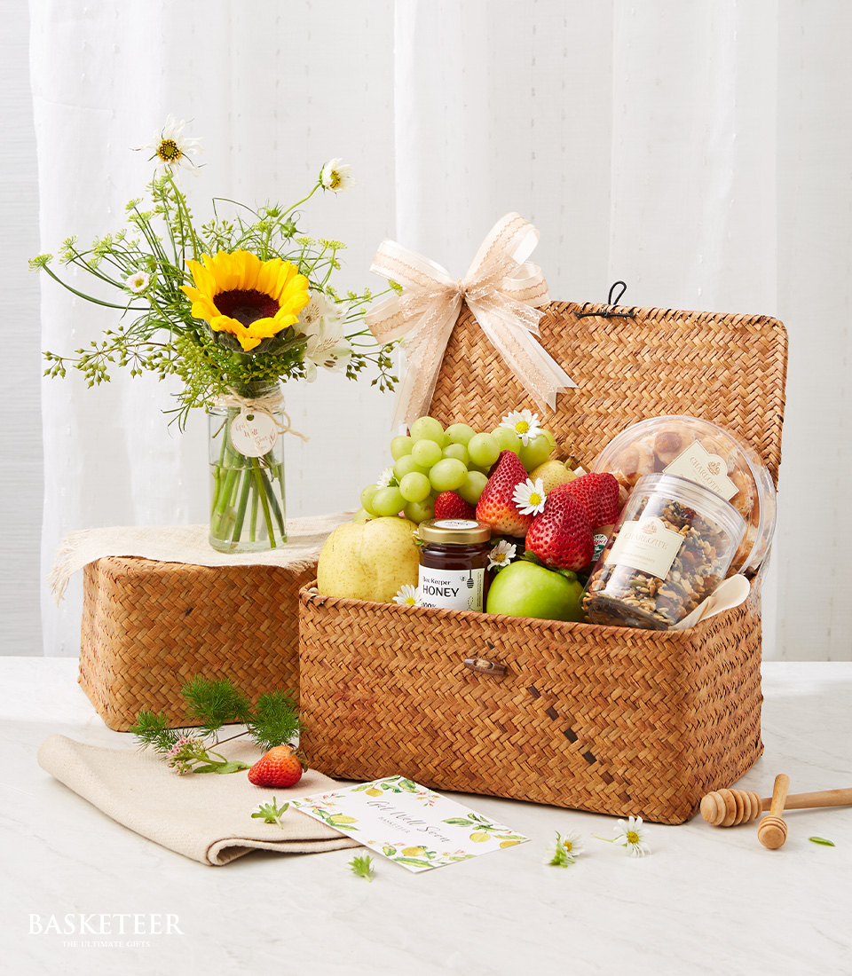 Fresh Fruits And Cookies In The Wicker Hamper With A Small Sunflower Vase