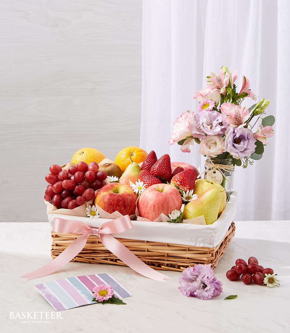 Fresh Fruits In The Basket With A Small Sweet Pink And Purple Flowers In a Vase