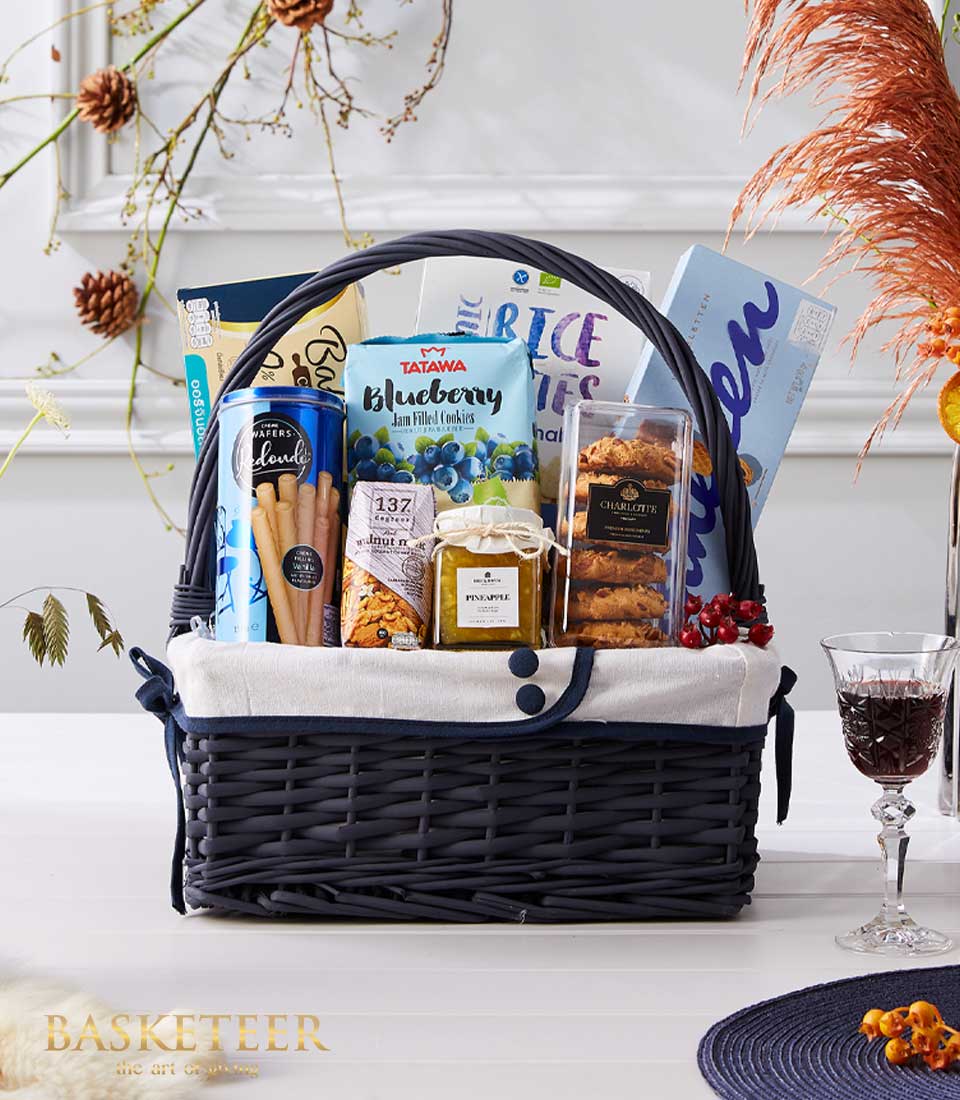 Cookies With Gourmet Food and Many Gift In The Navy Blue Basket With a Bow