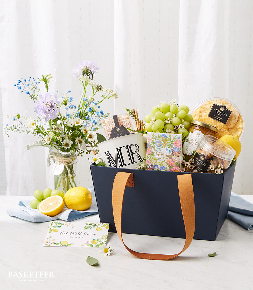 Fresh Fruits, Cookies And Mug In The Navy Blue Fashion Bag Box Brown Handle With A Small Bright Flowers Vase