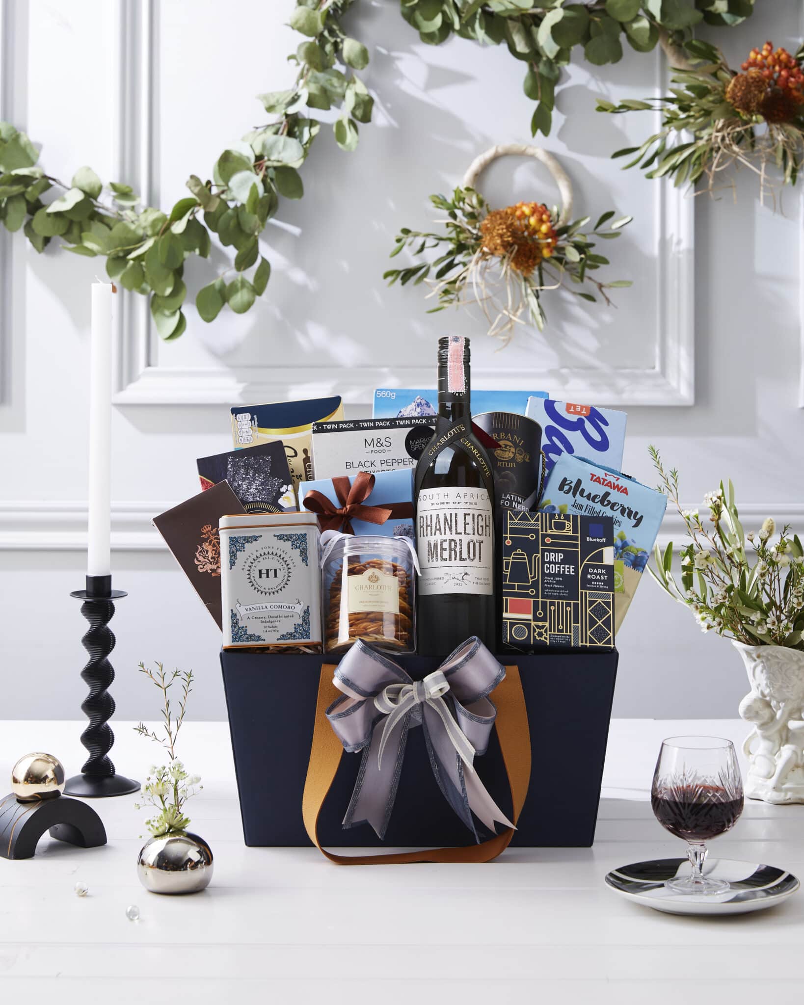 Elegant navy and gold gift basket with South African Merlot red wine, biscuits, drip coffee, tea, chocolates, and blueberry snacks