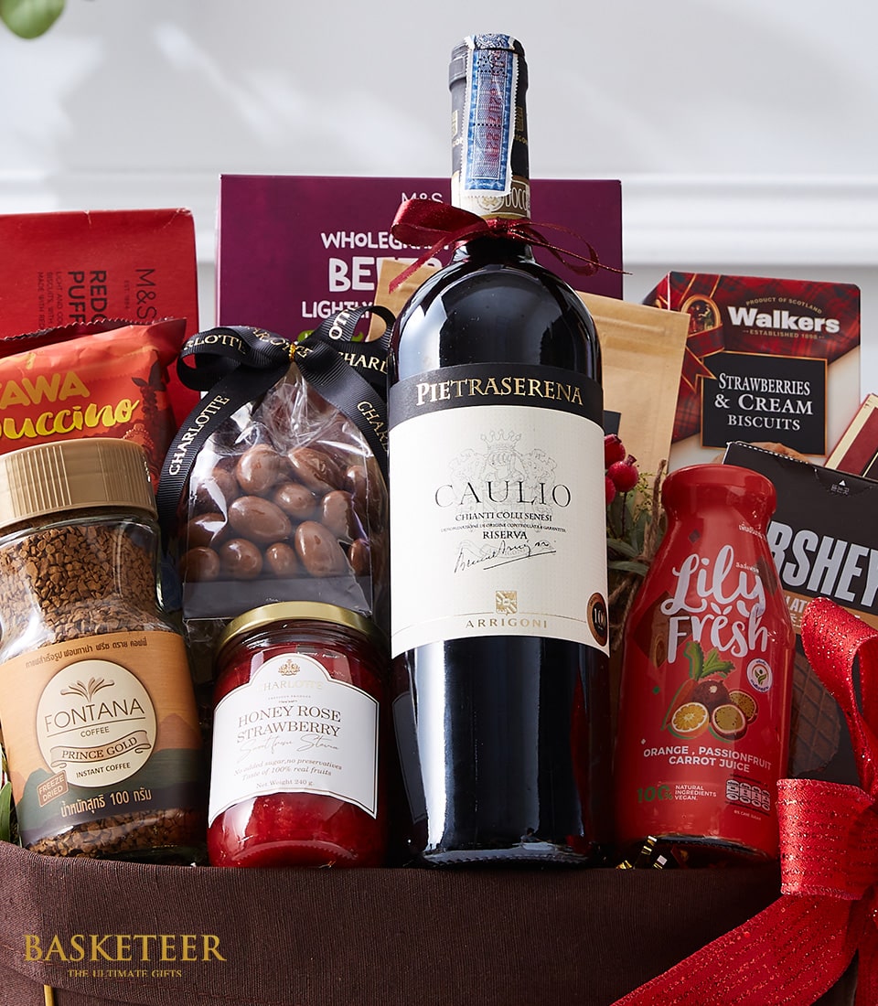 An exquisite gourmet gift basket meticulously curated by Basketeer, presenting a bottle of the distinguished Pietraserena Caullo red wine elegantly nestled alongside premium Fontana instant coffee. Indulge in velvety chocolate-covered almonds and artisanal honey rose strawberry jam, perfectly complemented by an array of delightful snacks such as Lily Fresh strawberry juice and classic Walkers biscuits. All these treats come artfully arranged within an opulent box adorned with the signature Basketeer ribbon, promising a luxurious experience from start to finish.