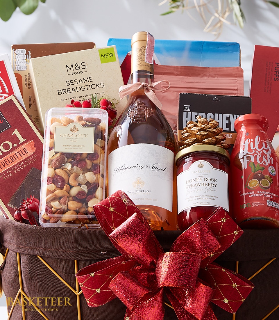An opulent Champagne & Gourmet Delights Basket curated by Basketeer, overflowing with indulgent treats. This luxurious hamper boasts a bottle of fine champagne, decadent M&S Sesame Breadsticks, a jar of exquisite Honey Rose Strawberry preserve, and an assortment of premium mixed nuts. Refresh your palate with the fresh and invigorating Lily Fresh drink while savoring rich chocolates and other gourmet delights. Elegantly adorned with a magnificent red bow and the distinguished Basketeer logo gracing the packaging, this sophisticated ensemble is an impeccable gift for any special occasion.