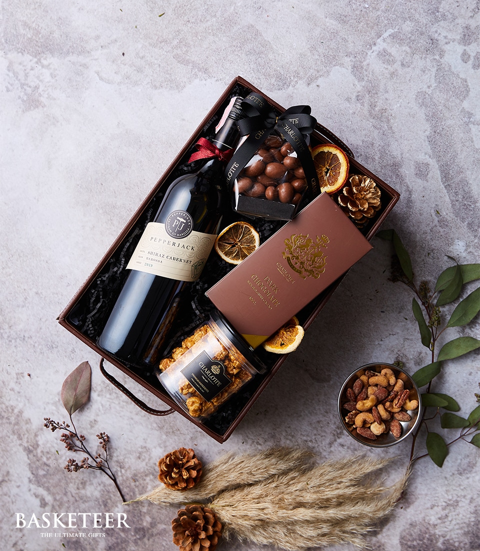 Gift box with Pepperjack Shiraz Cabernet wine, dark chocolate, nuts, caramel popcorn, and chocolate almonds