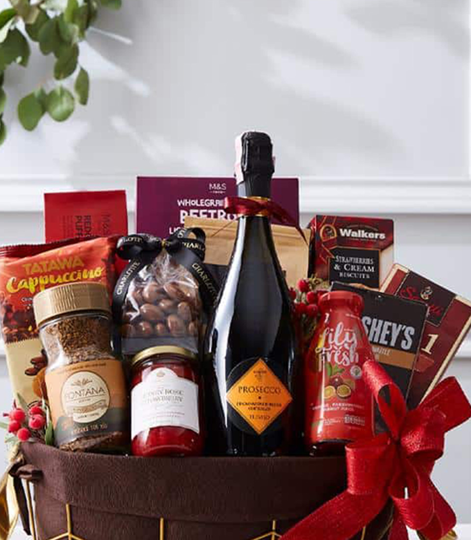 A premium gift basket filled with a bottle of fine wine, gourmet chocolates, nuts, and indulgent treats, elegantly wrapped with a festive red ribbon.
