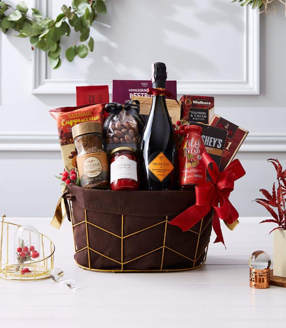A premium gift basket filled with a bottle of fine wine, gourmet chocolates, nuts, and indulgent treats, elegantly wrapped with a festive red ribbon.