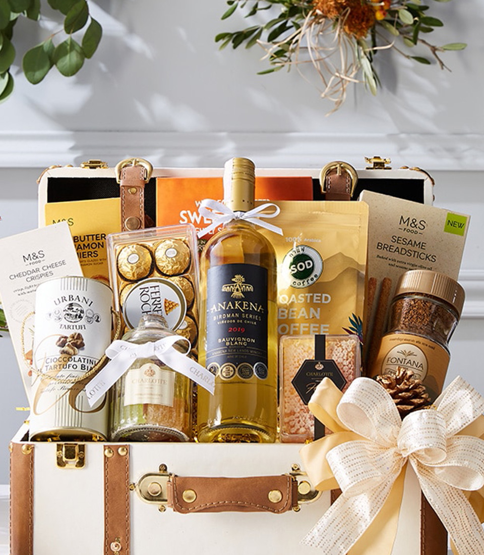 A luxurious gourmet gift hamper filled with fine white wine, artisanal chocolates, premium coffee, and gourmet snacks, elegantly presented in a vintage-inspired leather trunk.